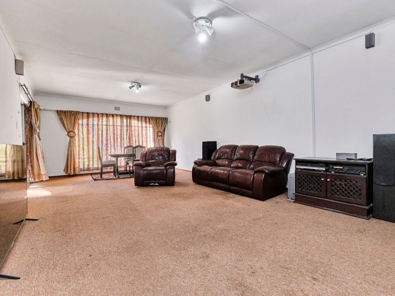 Spacious living area featuring wall-to-wall carpeting, a ceiling-mounted projector, and large sliding glass doors providing natural light.