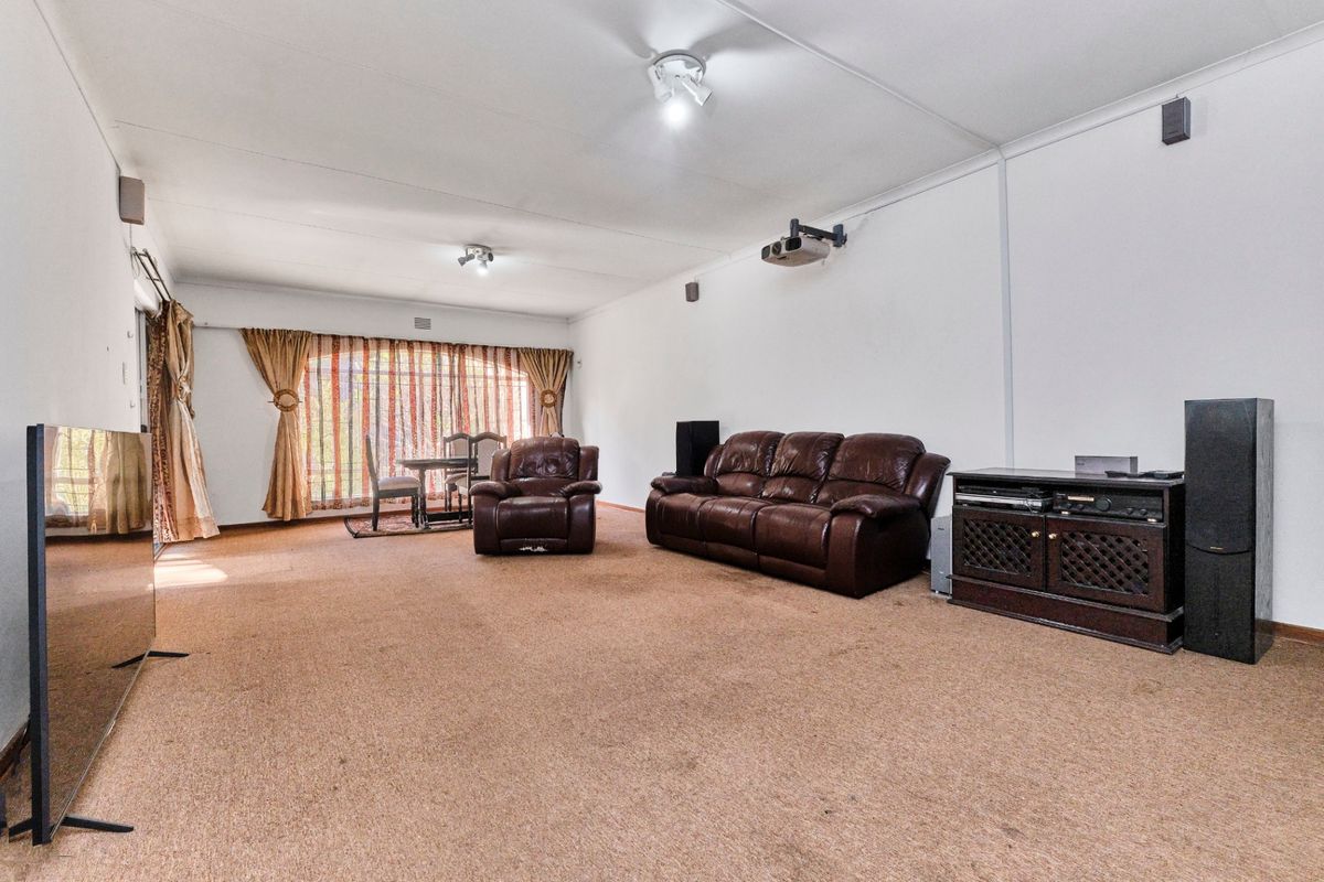 Spacious living area featuring wall-to-wall carpeting, a ceiling-mounted projector, and large sliding glass doors providing natural light.