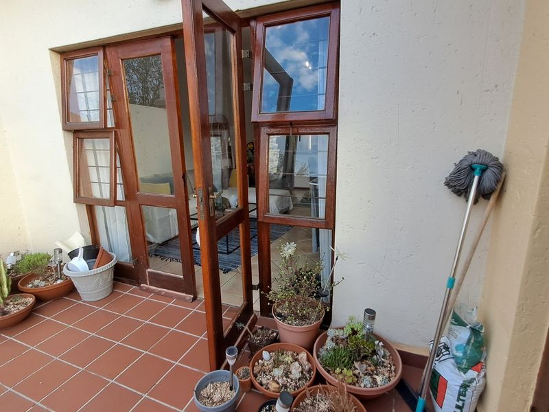 A private patio area featuring terracotta floor tiles and timber-framed glass doors providing access to the interior living space.