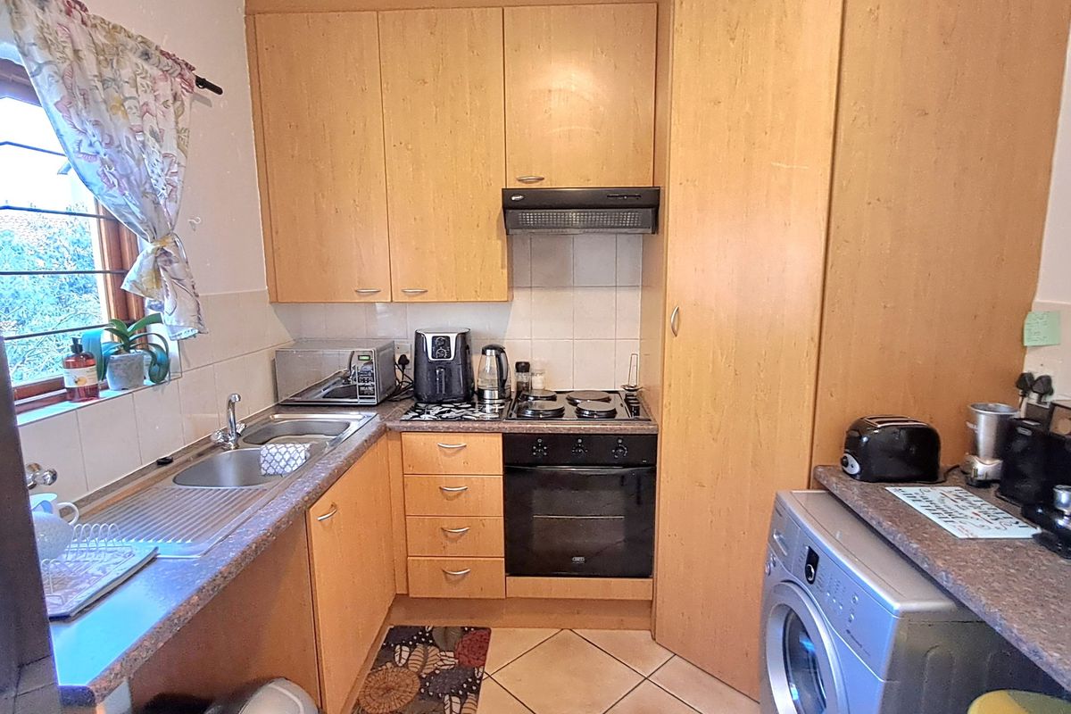 Compact kitchen featuring laminate cabinetry, built-in oven with extractor fan, stainless steel sink, and tiled flooring.