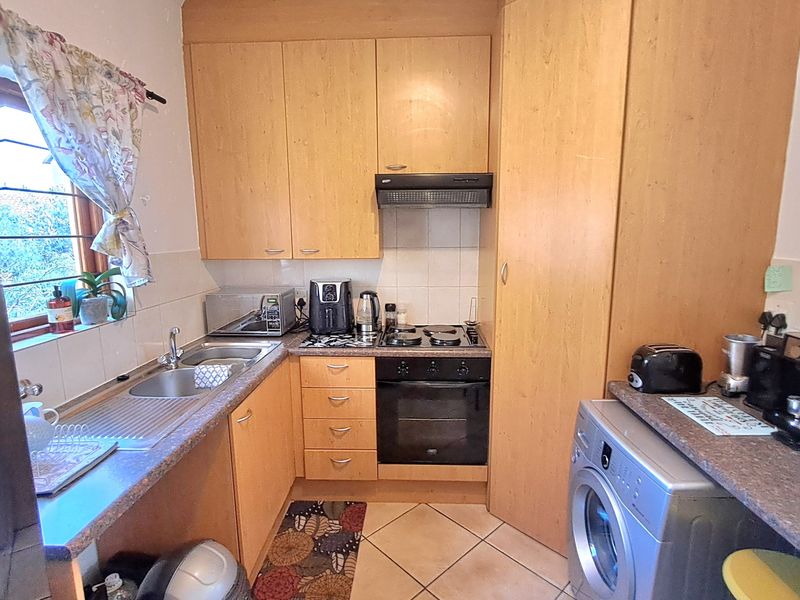 Compact kitchen featuring laminate cabinetry, built-in oven with extractor fan, stainless steel sink, and tiled flooring.