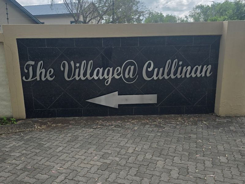 Entrance signage for The Village at Cullinan featuring a stone-clad boundary wall and paved driveway access.
