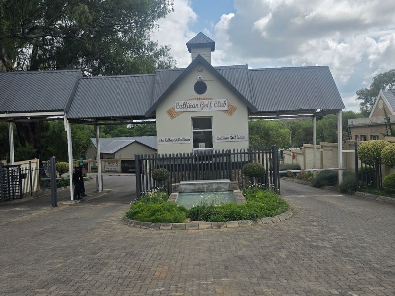 The main entrance gate to the Cullinan Golf Estate, featuring a paved driveway, security boom, and a central water feature.