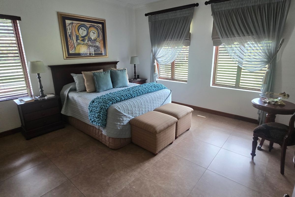 Spacious bedroom featuring large format floor tiles, a timber-look ceiling with a central fan, and window shutters providing natural light control.