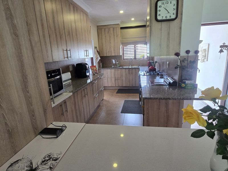 A well-maintained kitchen featuring wood-look cabinetry, granite countertops, built-in oven, and a distinctive tongue and groove ceiling with recessed lighting.