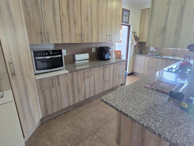 A functional kitchen featuring light wood-grain cabinetry, granite countertops, built-in oven, and tiled flooring with a clean, practical layout.