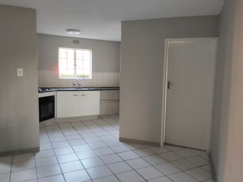 A functional, empty kitchen featuring tiled flooring, built-in cabinetry, a hob, and an oven, ready for a modern update.