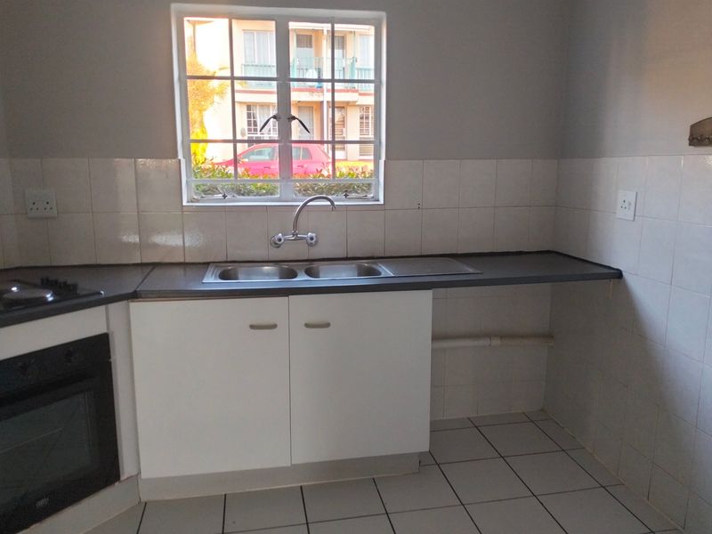 A functional kitchen featuring a double sink, built-in oven, hob, tiled splashback, and white base cabinetry with laminate countertops.