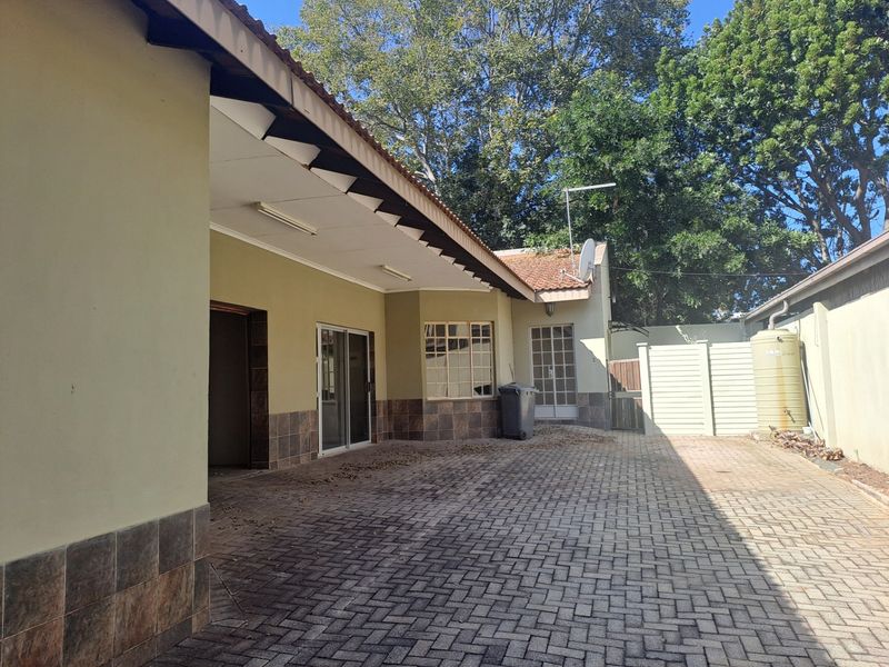 Rear exterior view of the townhouse featuring a paved courtyard area, sliding door access, and a water storage tank.
