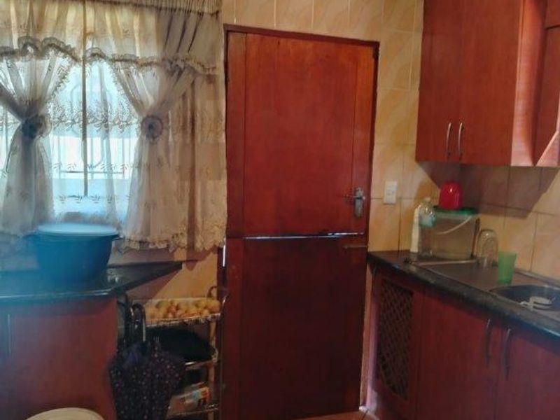 A functional kitchen featuring wooden cabinetry, tiled backsplash, and a stable door, offering a dated aesthetic with potential for modernization.