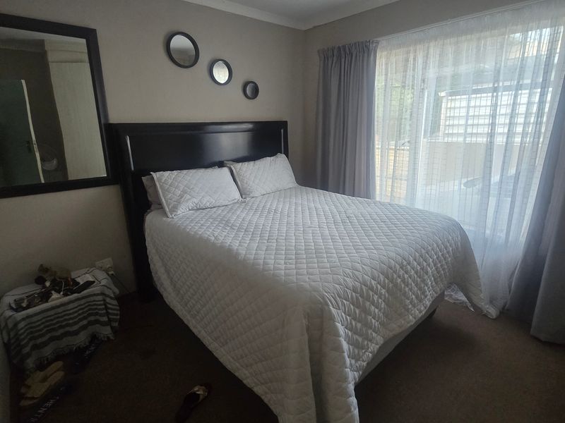 A standard bedroom featuring carpeted flooring and large windows with curtain tracks, providing natural light and a functional layout for a townhouse.