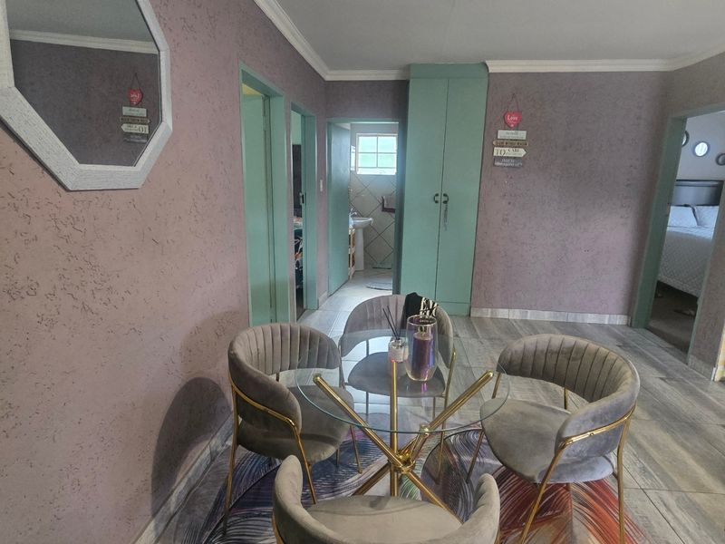 A living area featuring textured walls, laminate flooring, and a built-in cupboard, providing access to adjacent rooms.