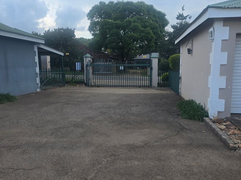 Front exterior view of the townhouse property featuring a paved driveway, secure metal gate, and garage access.