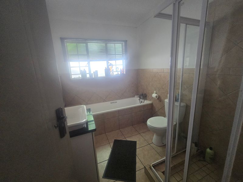 A functional bathroom featuring a bathtub, separate shower enclosure, toilet, and vanity basin with tiled finishes throughout.