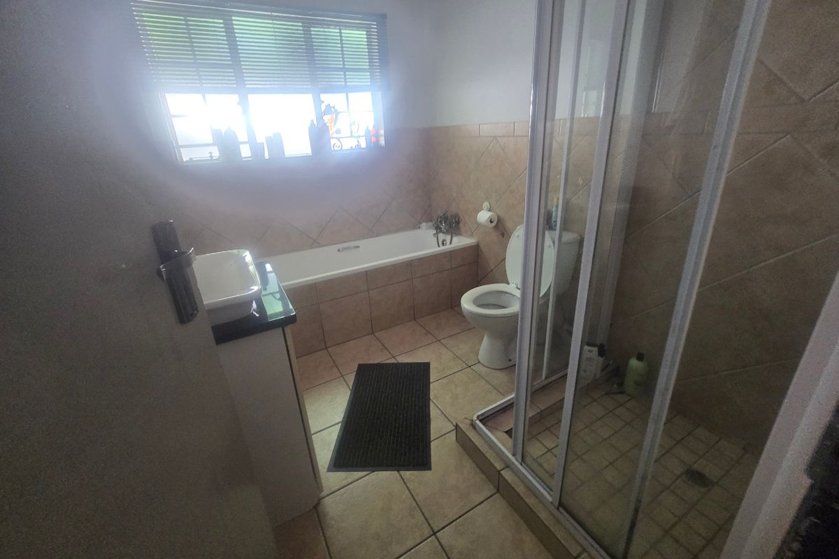 A functional bathroom featuring a bathtub, separate shower enclosure, toilet, and vanity basin with neutral tiled finishes.