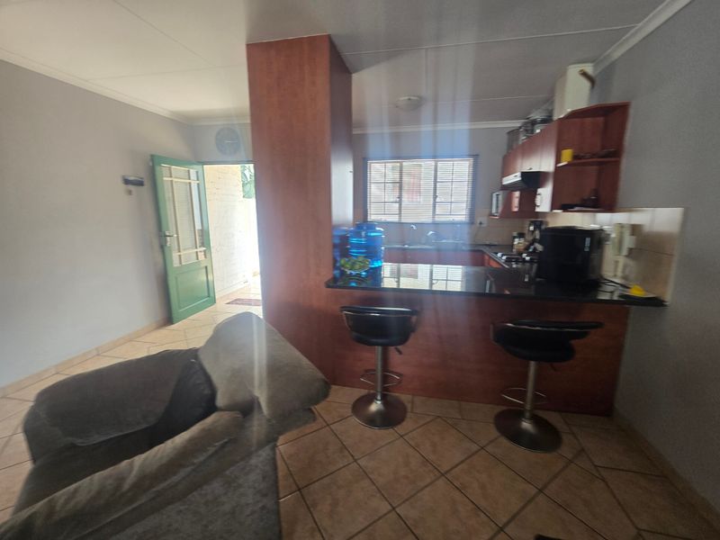 Open-plan living and kitchen area featuring a breakfast bar, granite countertops, and tiled flooring, providing a functional and connected living space.