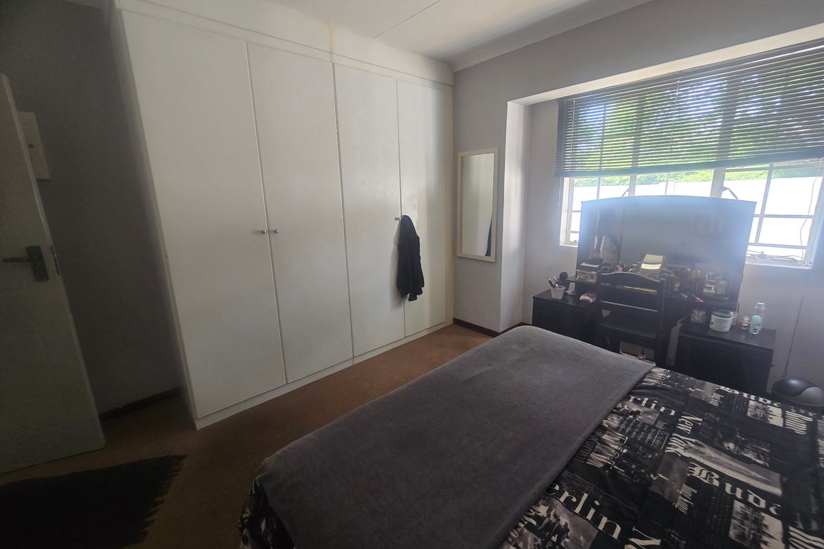 A bedroom featuring built-in cupboards, cove cornicing, and venetian blinds, offering a functional space with potential for cosmetic updates.
