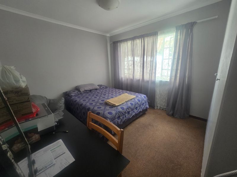 A standard bedroom featuring neutral wall finishes, carpeted flooring, and a built-in wardrobe, offering a functional space with natural light.