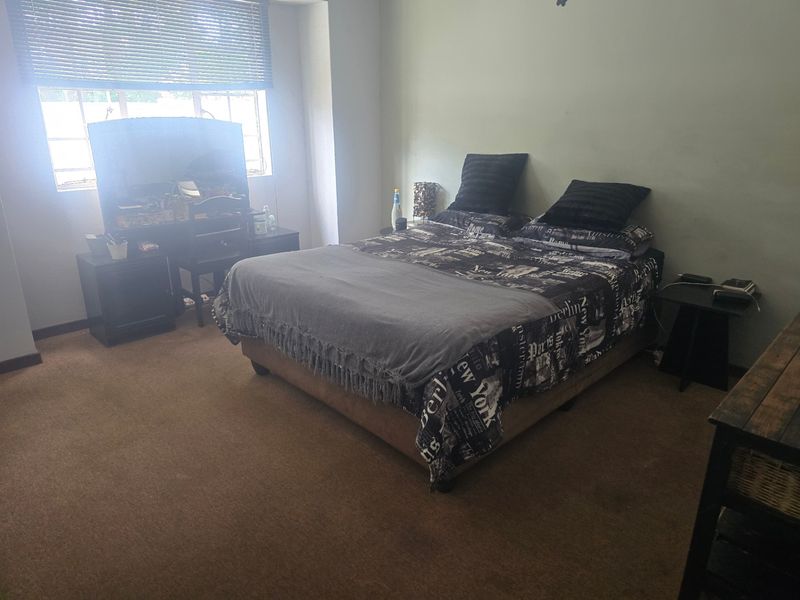 A standard bedroom featuring carpeted flooring and venetian blinds, providing a functional space with neutral wall finishes.