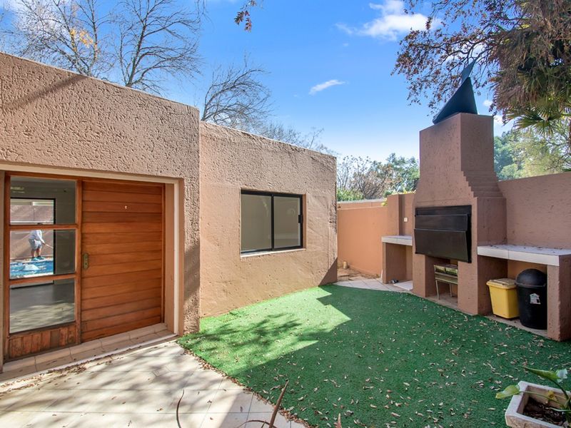 Outdoor patio area featuring a built-in braai, tiled flooring, and artificial grass, providing a functional space for outdoor entertaining.
