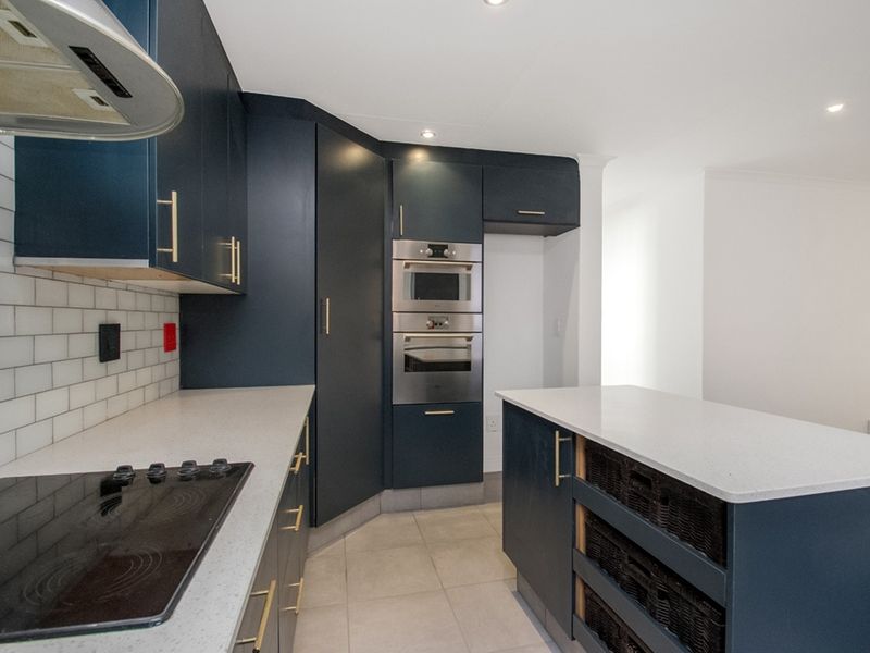 Modern kitchen featuring dark blue cabinetry, quartz countertops, subway tile backsplash, built-in oven, microwave, and a functional kitchen island.