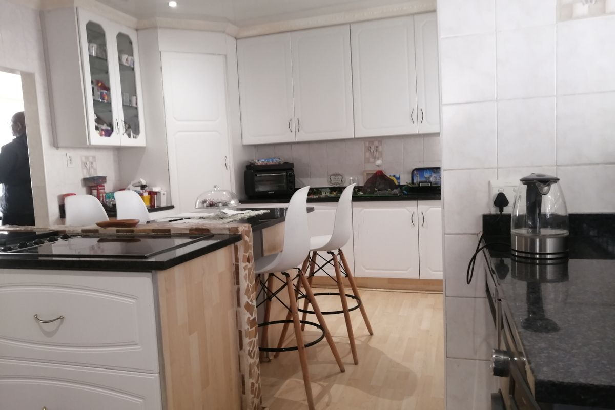 A functional kitchen featuring white cabinetry, granite countertops, a central island, and tiled backsplash with integrated oven and recessed lighting.