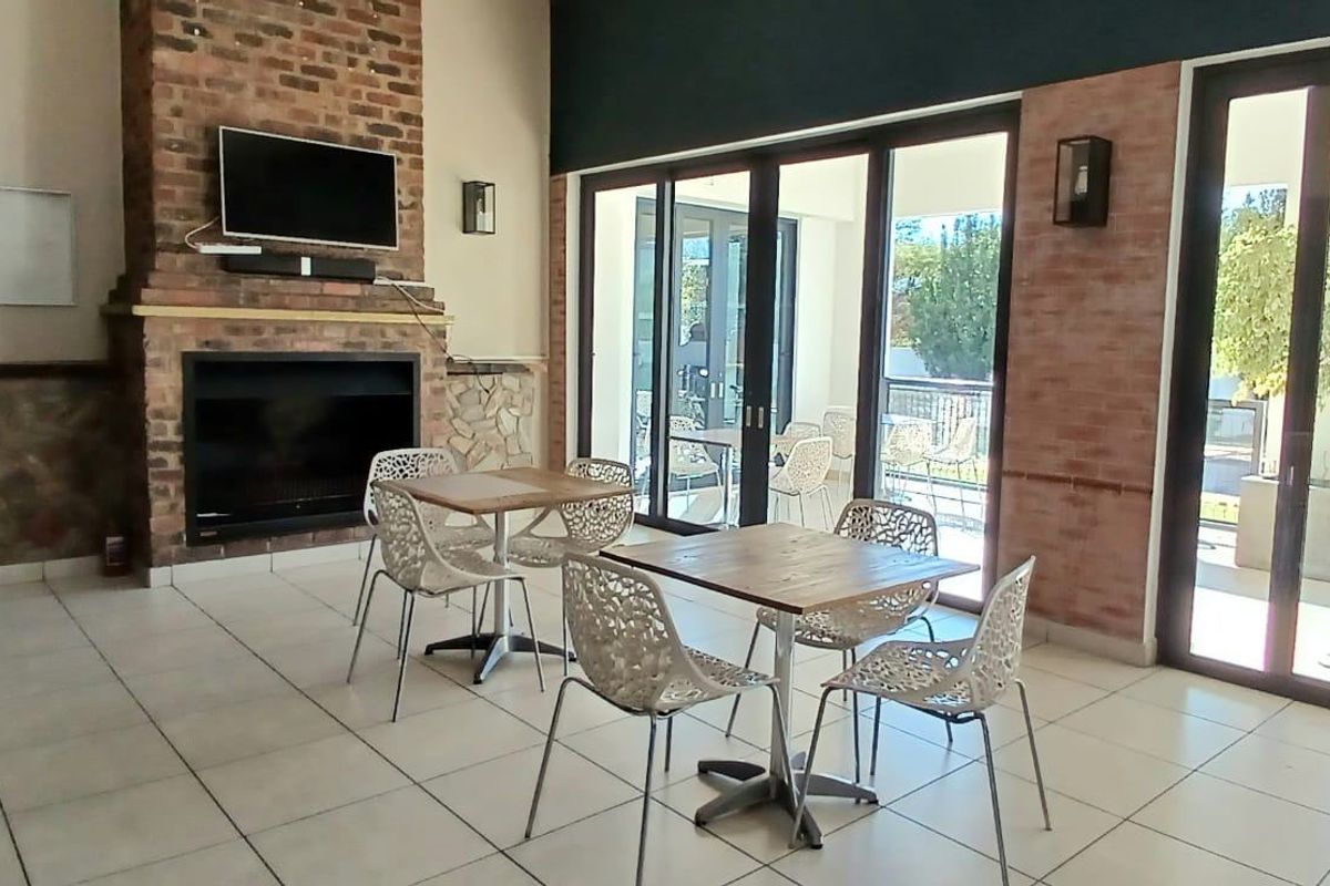 A spacious living area featuring a prominent brick fireplace, tiled flooring, and large aluminium sliding doors providing access to the outdoor area.