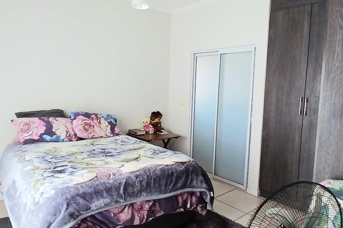 A bedroom featuring tiled flooring and a built-in wardrobe with dark wood-look finish and a secondary sliding door access.
