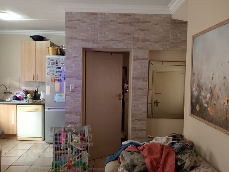 Open plan living area featuring a functional kitchen with cabinetry, tiled flooring, and decorative stone-look wall cladding around the doorway.