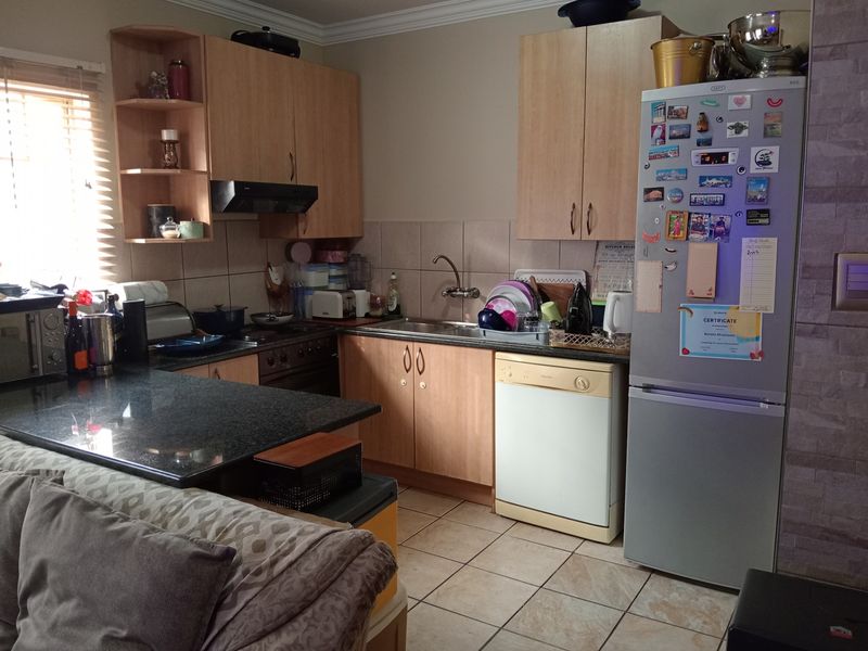 A functional kitchen featuring laminate cabinetry, granite countertops, tiled splashbacks, and ceramic floor tiles, offering a practical layout for daily meal preparation.