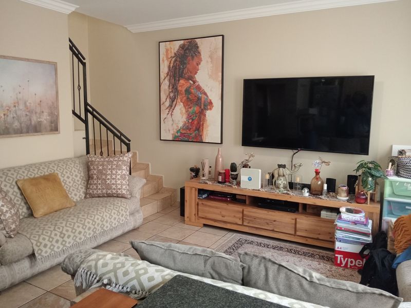 A comfortable living room featuring tiled flooring, crown molding, and a staircase with a decorative wrought iron railing.