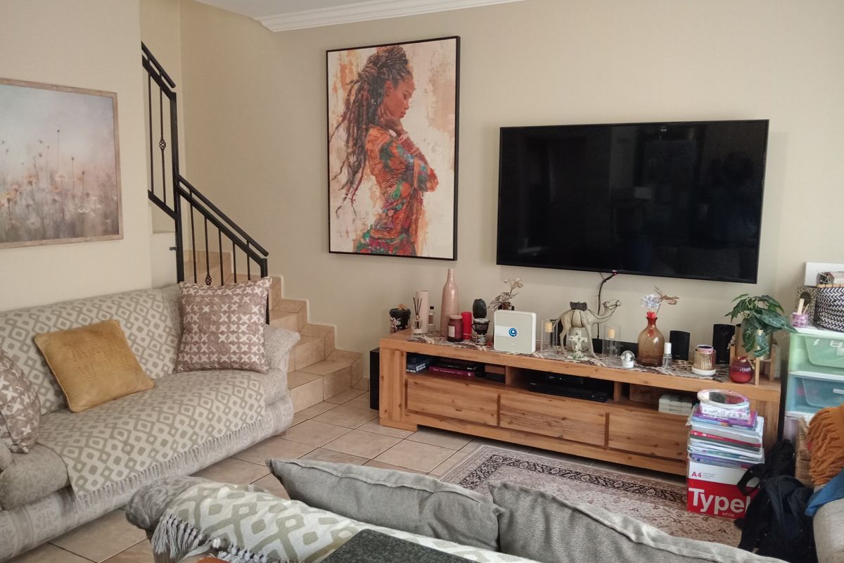 A comfortable living room featuring tiled flooring, crown molding, and a staircase with a decorative wrought iron railing.