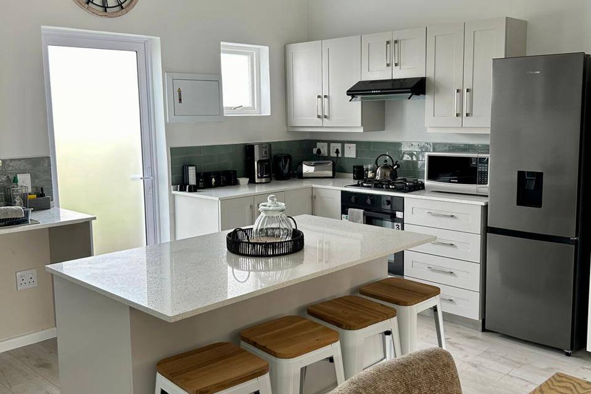 Modern kitchen featuring a central island with quartz countertops, ample built-in cabinetry, a gas hob, and a stylish tiled backsplash.