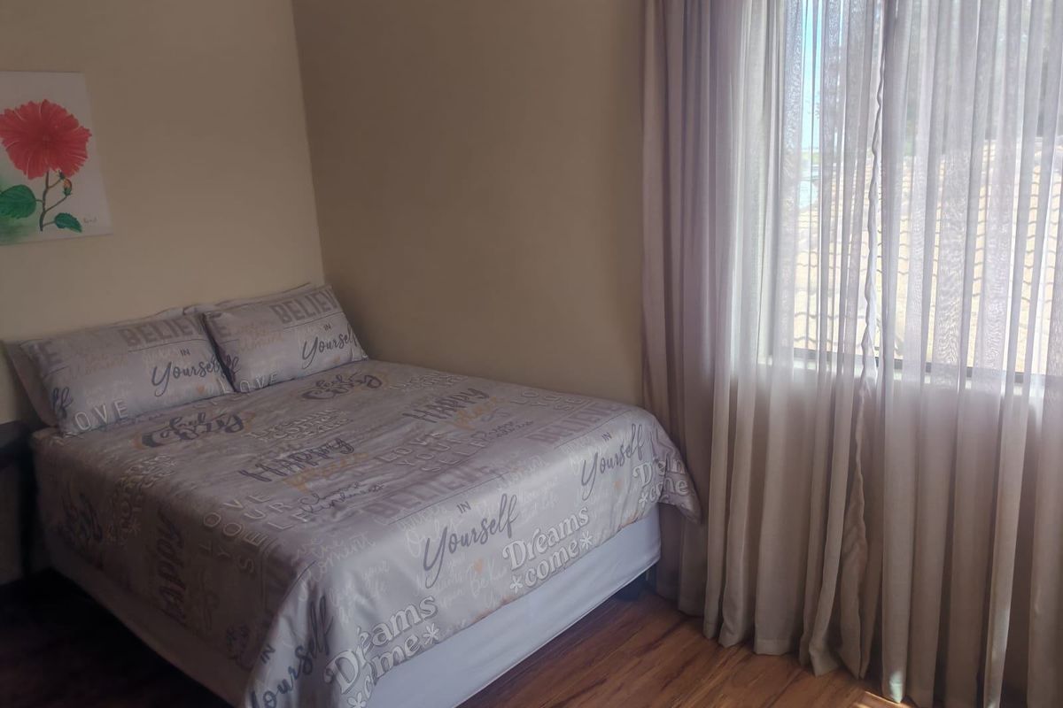 A standard bedroom featuring laminate flooring and large windows with installed curtain tracks, providing natural light.
