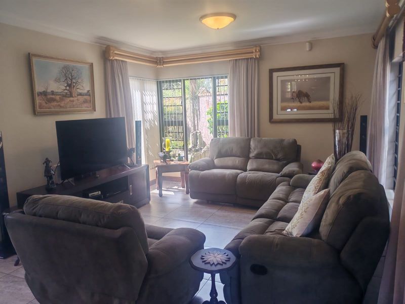 A comfortable living room featuring tiled flooring, a corner window with security bars, and classic ceiling cornicing, providing a functional and well-lit space.