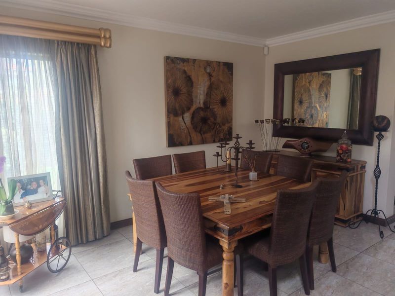 A well-maintained dining room featuring neutral wall tones, tiled flooring, and decorative crown molding, providing a comfortable space for formal dining.