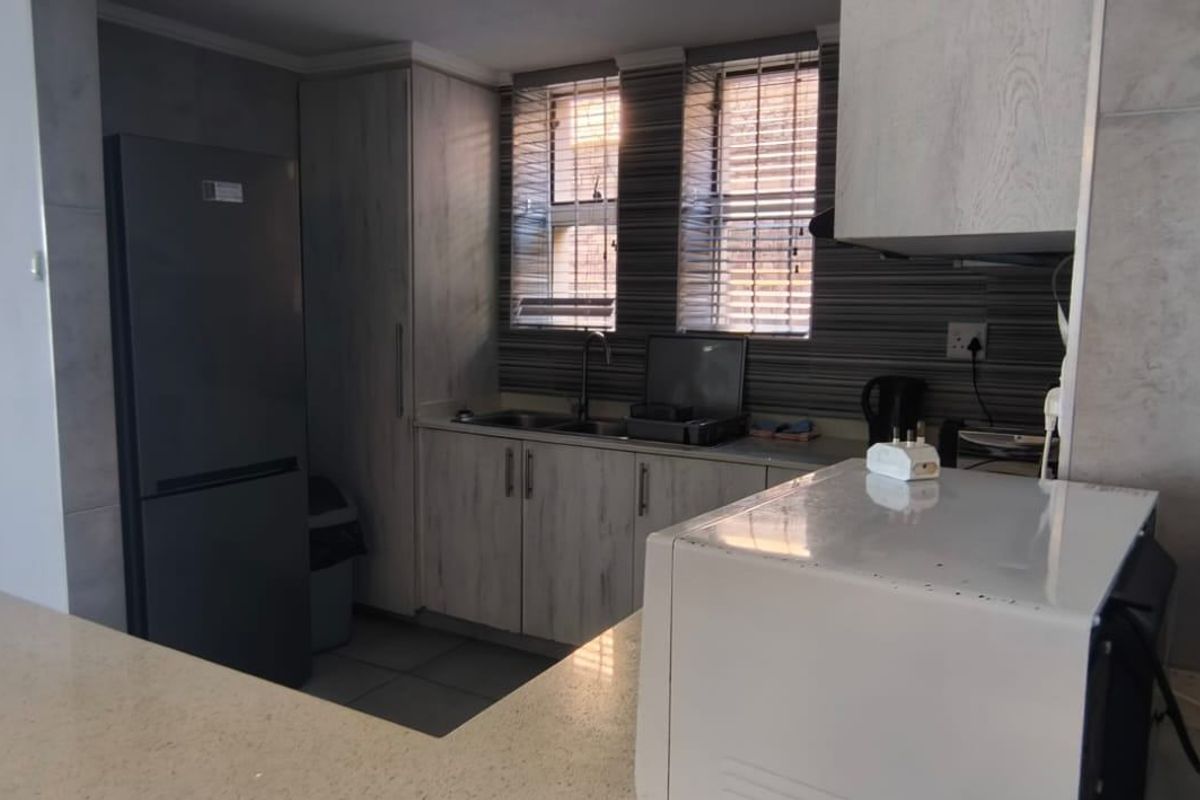 A functional kitchen featuring built-in cabinetry, a double sink, and ample countertop space, finished with modern tiled flooring.
