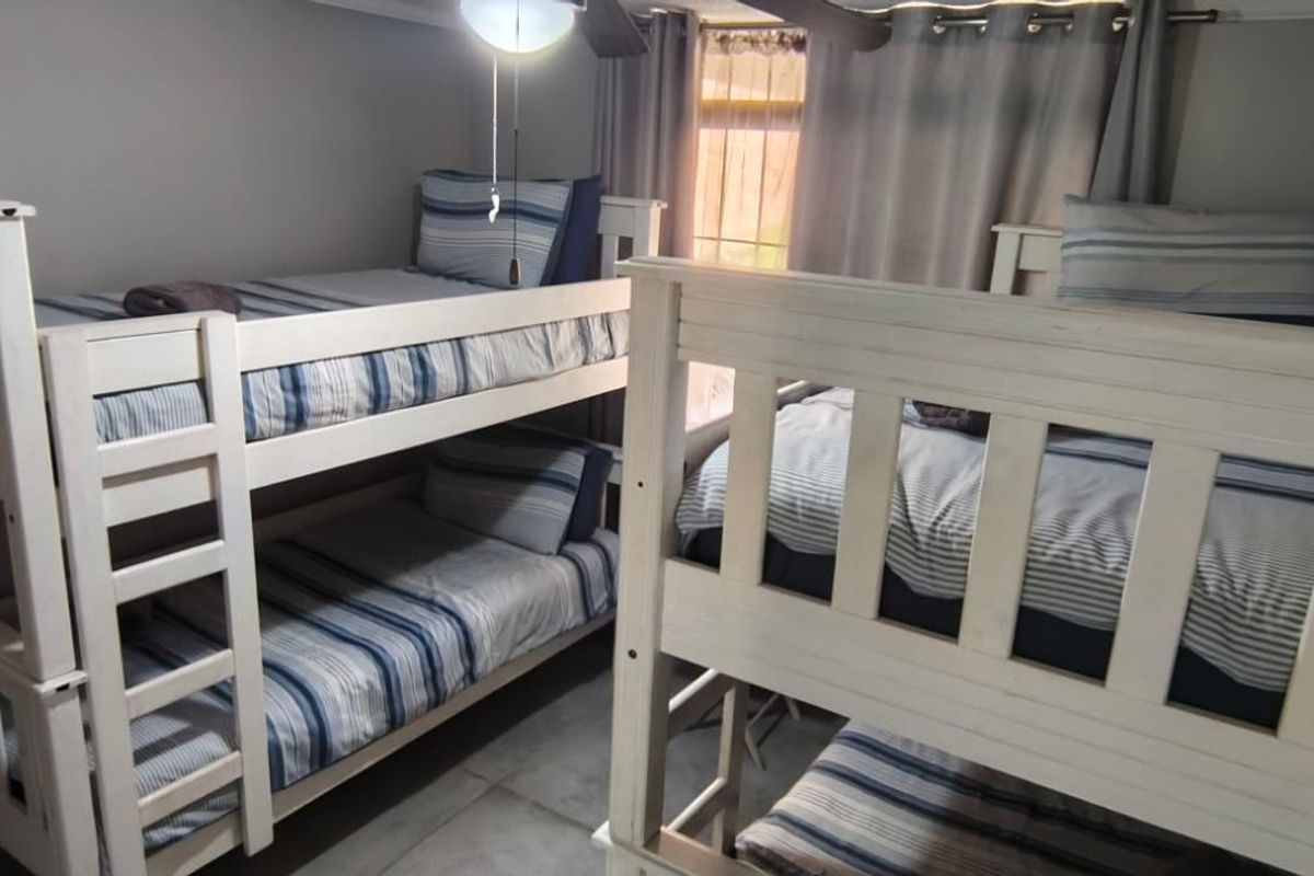 A bedroom featuring tiled flooring and a ceiling fan, currently configured with multiple bunk beds.