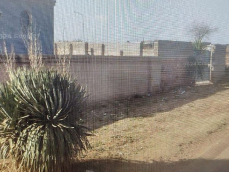 Street view showing the property boundary, including a perimeter wall and pedestrian gate access.