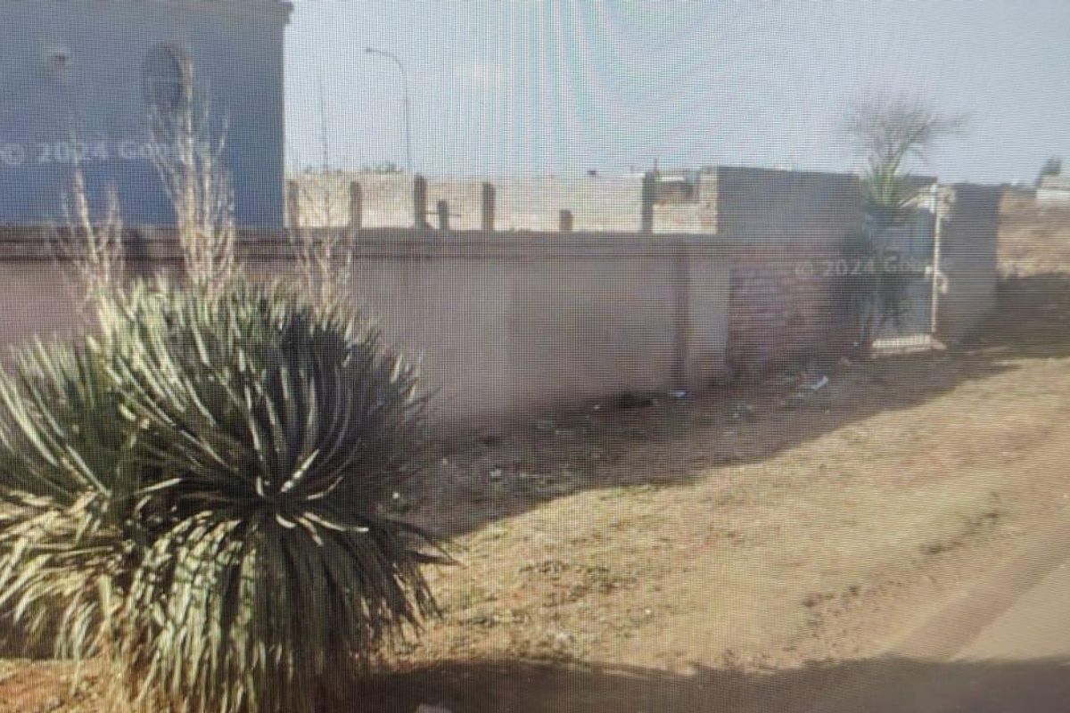 Street view showing the property boundary, including a perimeter wall and pedestrian gate access.