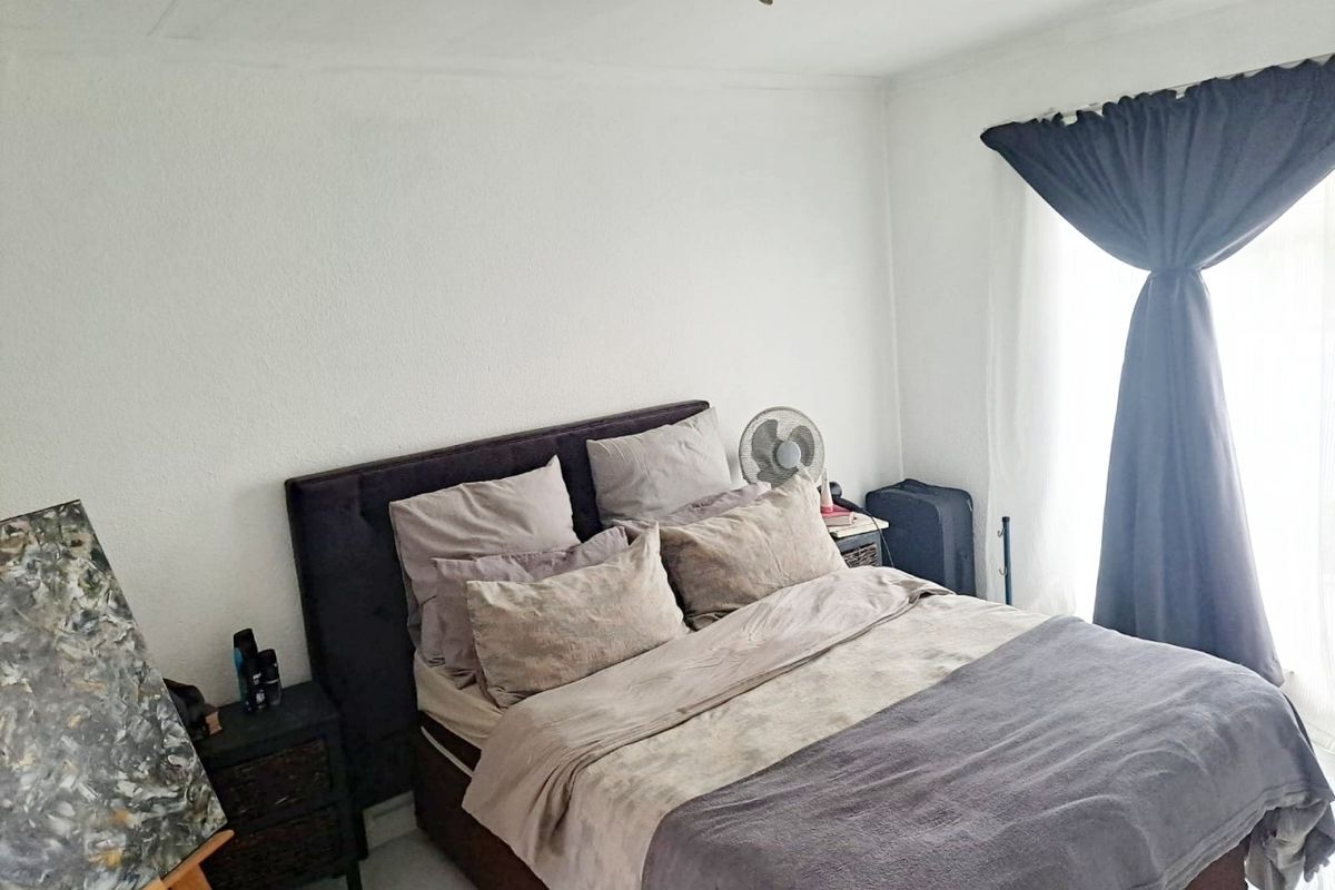 A bedroom featuring neutral walls and a window with dark curtains, providing a functional and simple living space.