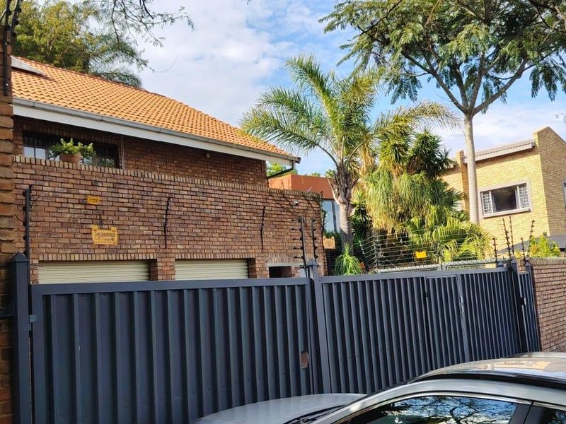 Front exterior view of a commercial property featuring a face brick facade, secure metal gate, and electric fencing.