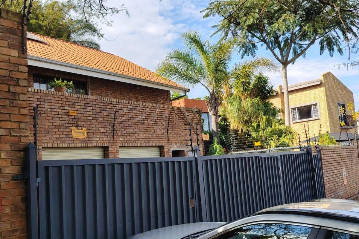 Front exterior view of a commercial property featuring a face brick facade, secure metal gate, and electric fencing.