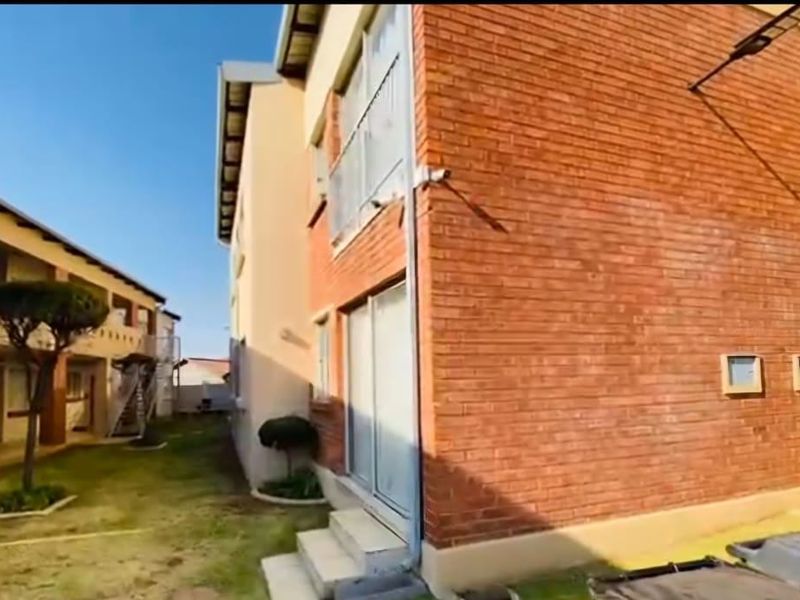 Exterior view of a commercial building featuring exposed brickwork, sliding glass doors, and a small balcony area.