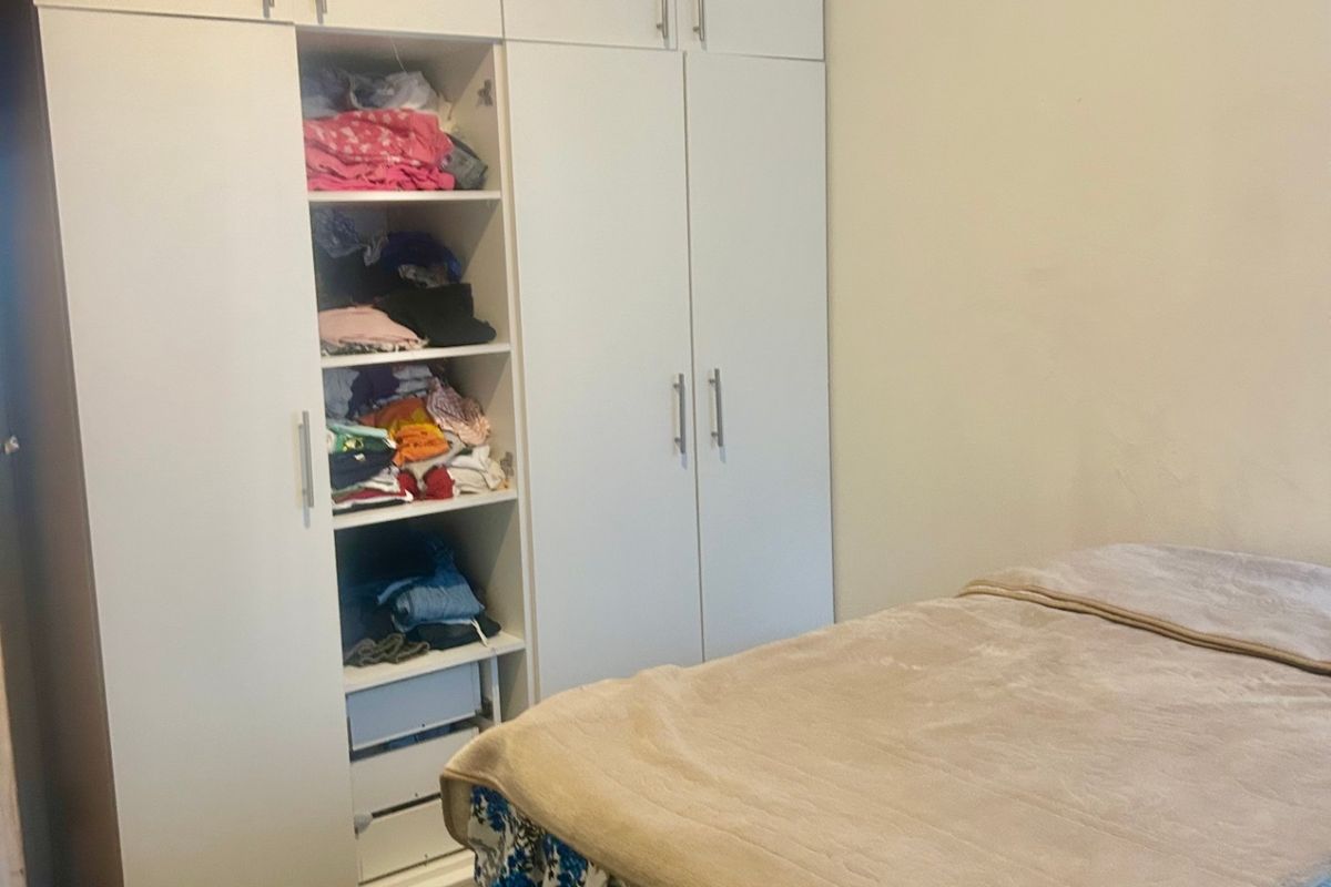 A bedroom featuring a large, white built-in wardrobe with ample storage space.