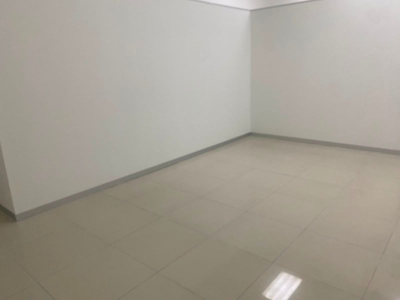 A clean, empty commercial office space featuring neutral tiled flooring and plain white walls, suitable for a variety of business configurations.