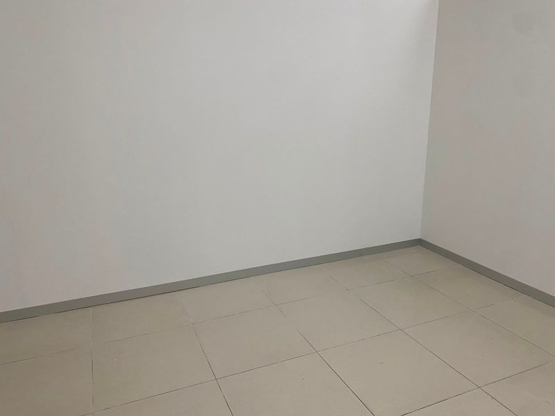 A clean, empty office space featuring neutral tiled flooring and simple wall finishes, suitable for a variety of commercial uses.