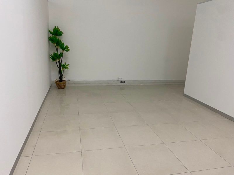 A clean, empty commercial office space featuring neutral tiled flooring and white walls, suitable for a variety of business configurations.