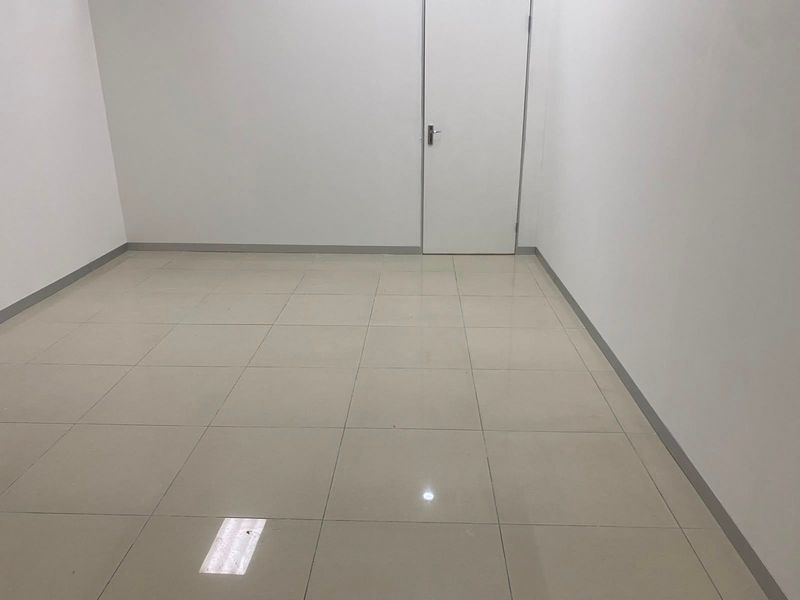 A clean, vacant office space featuring neutral ceramic floor tiles and a simple interior door, ready for commercial fit-out.