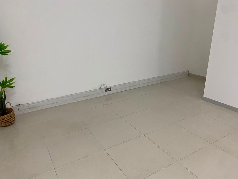 A vacant commercial office space featuring neutral tiled flooring, white walls, and integrated electrical power outlets.